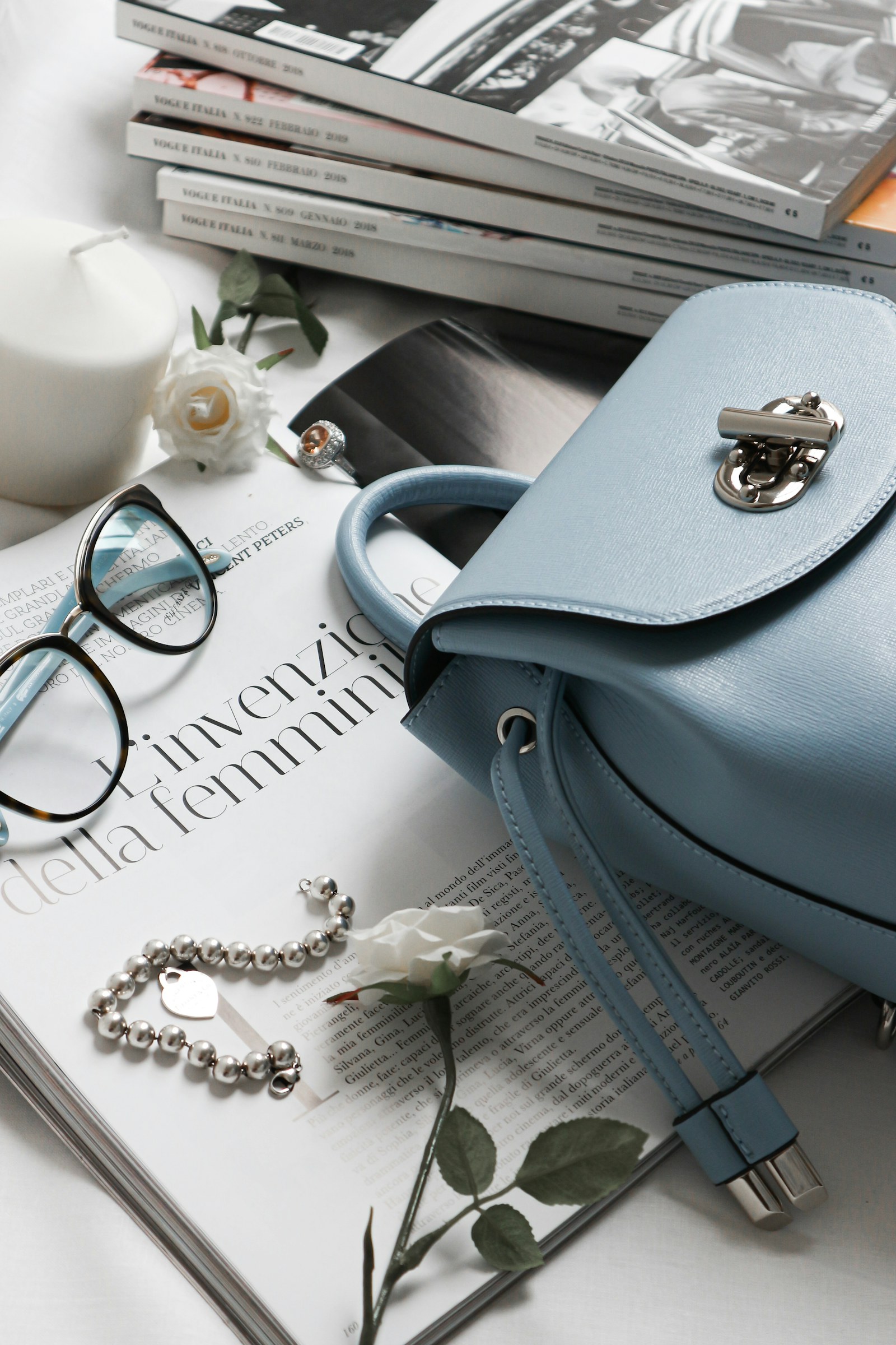 Light blue handbag with a silver clasp beside a magazine