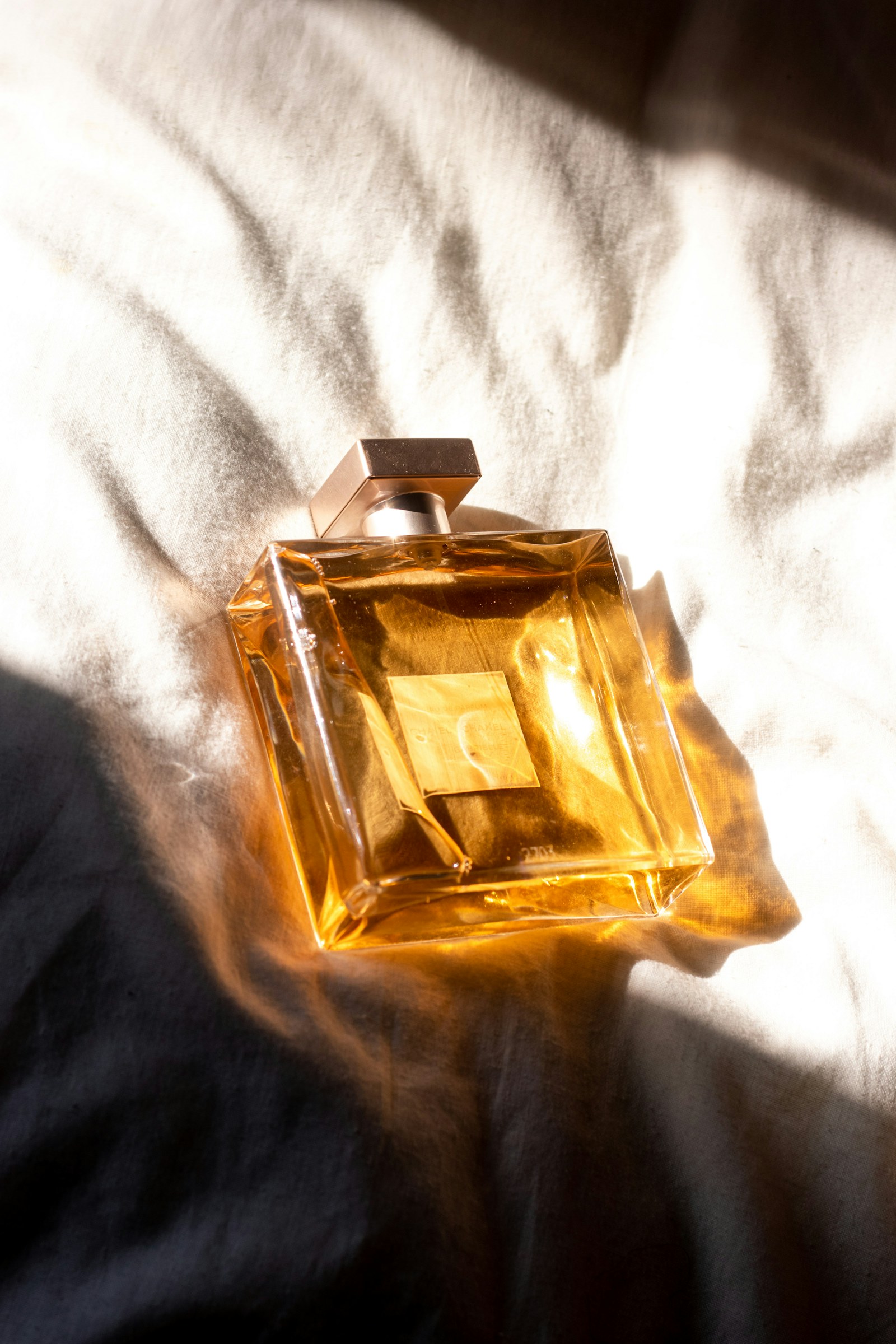 Amber glass perfume bottle in sunlight on a white sheet