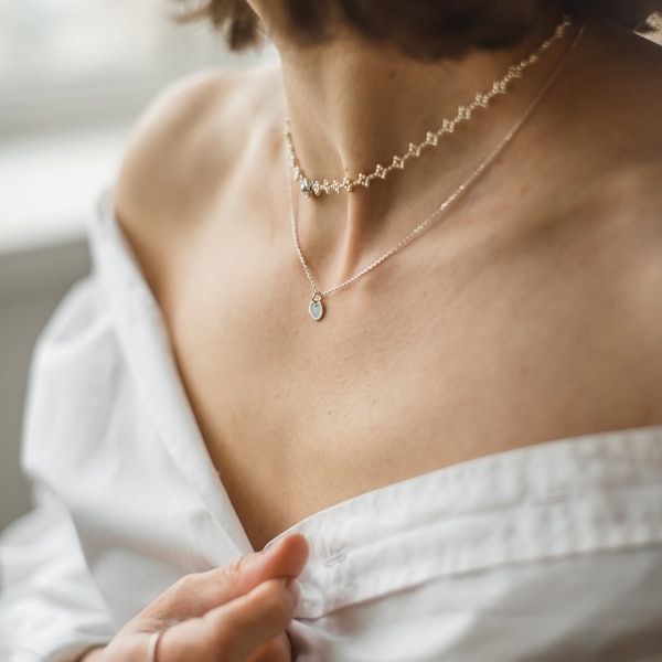 Layered gold necklaces worn with a white shirt