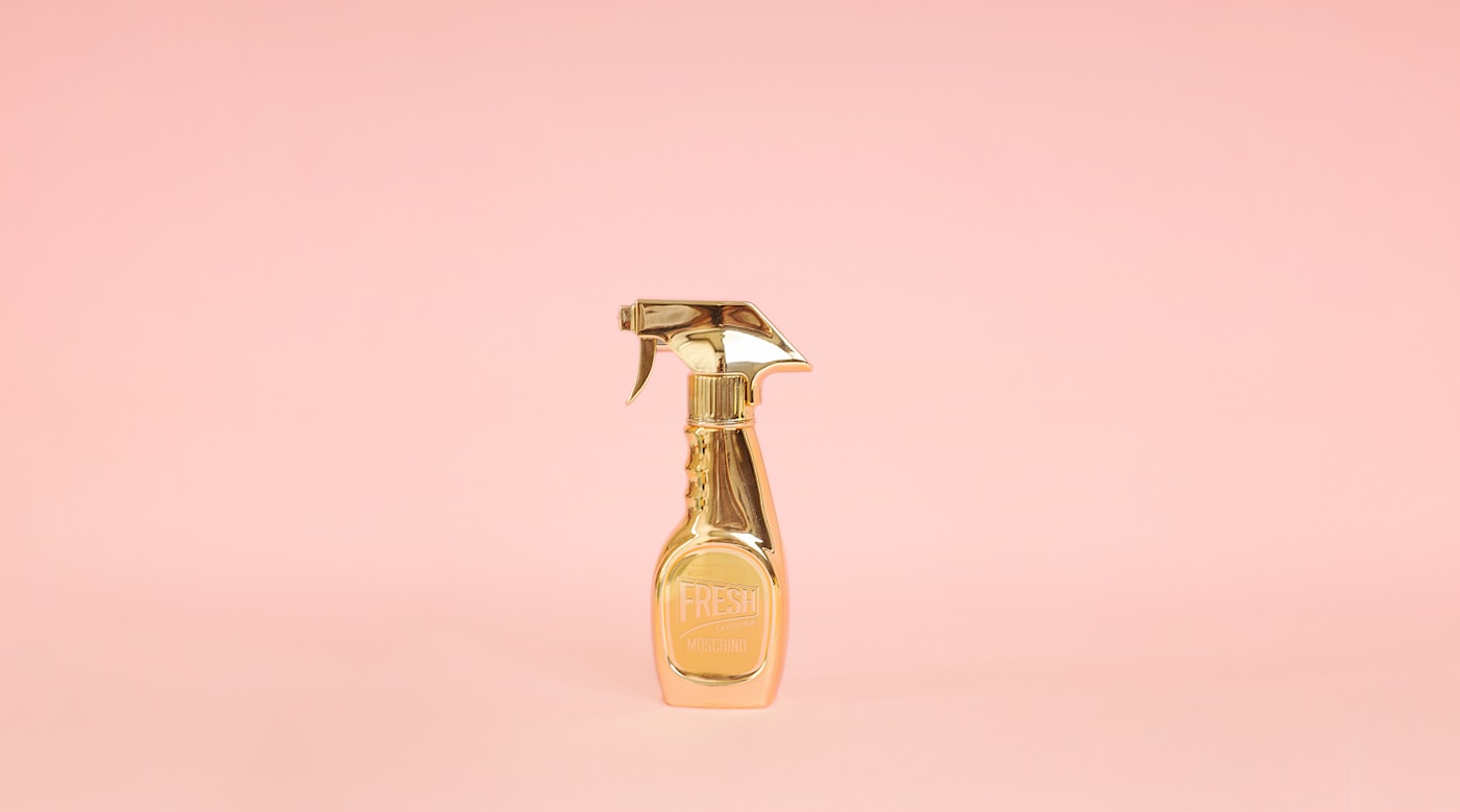 Gold perfume spray bottle on a pink background
